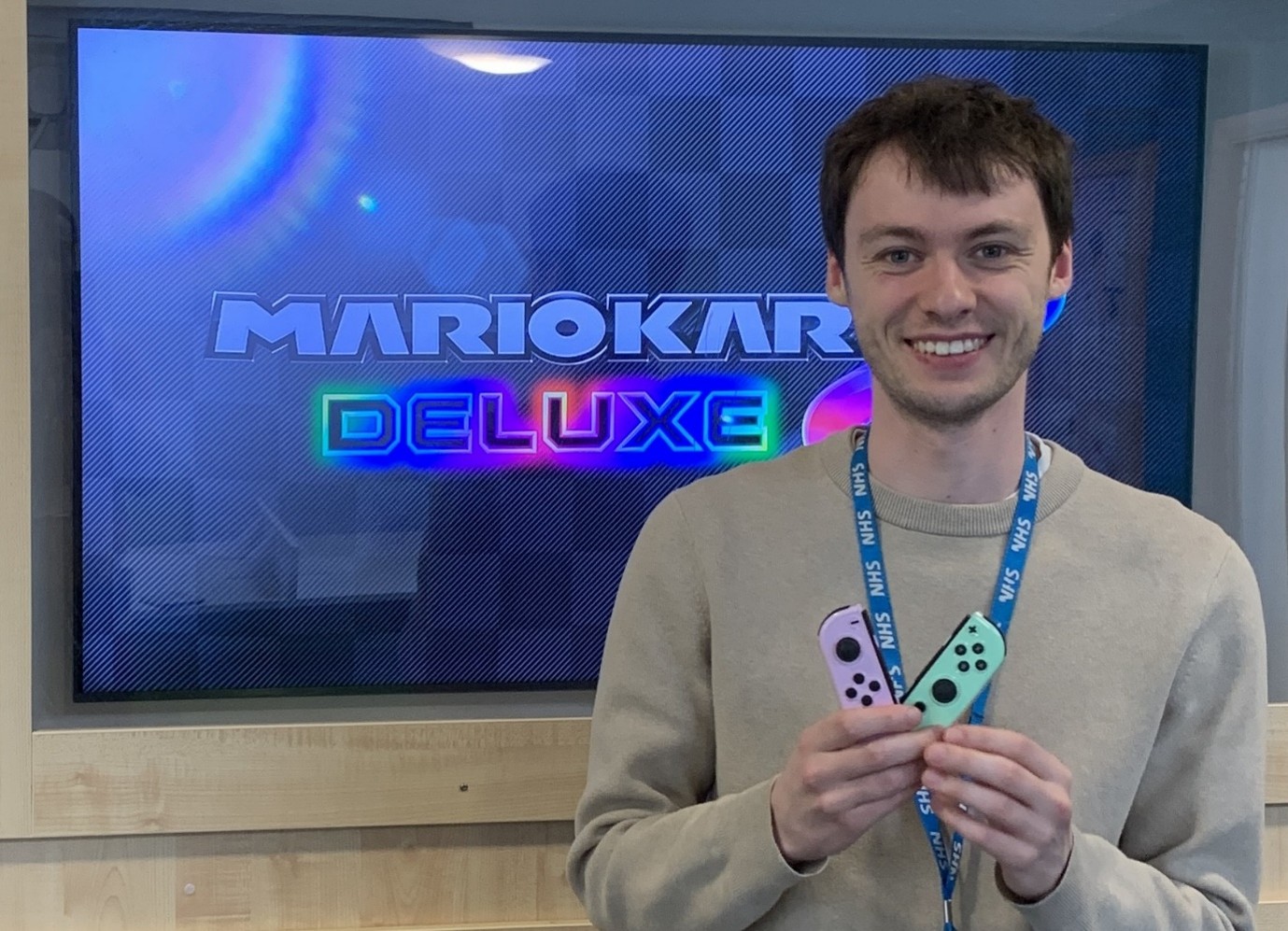 Lavender Ward staff member shows off Joycons in front of TV displaying Mario Kart 8